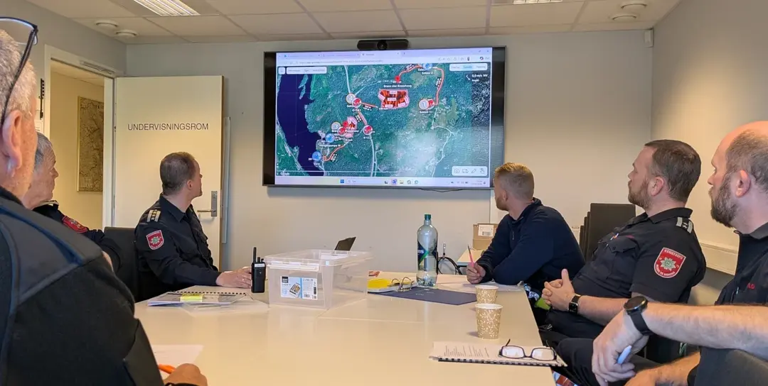 Tactical commanders in a training classroom reviewing a live Syncmap exercise on a large screen